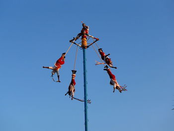 Low angle view of pole swingers against clear blue sky