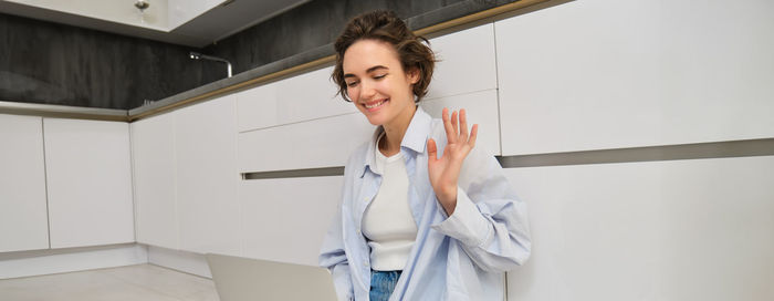 Portrait of young woman standing against wall