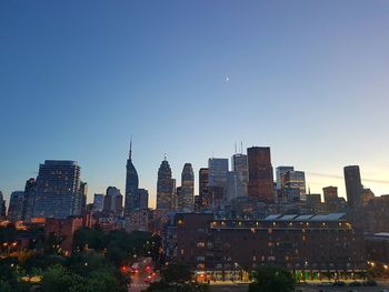 Illuminated buildings in city against clear sky