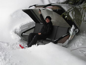 Portrait of woman sitting on abandoned ski lift on snow