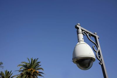 Low angle view of security camera against clear blue sky