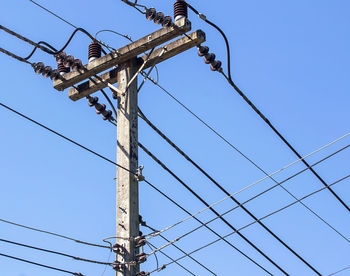 Low angle view of electricity pylon against clear sky