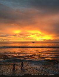 Silhouette people standing on beach against sky during sunset