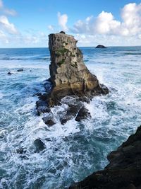 Rock formation on sea shore against sky