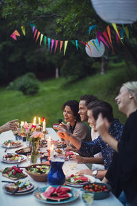 Happy friends talking while enjoying meal at garden party