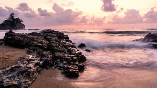 Water splashing on rocks against cloudy sky at dusk