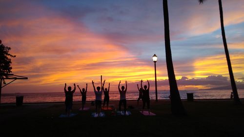 Silhouette people playing on beach against sky during sunset