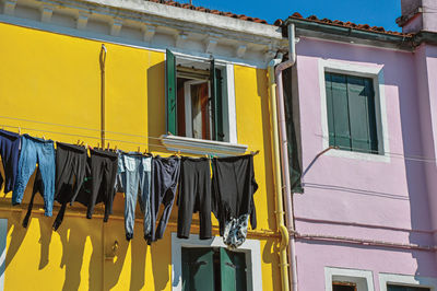 Windows on colorful walls and clothes hanging in burano, a little town full of canals in italy