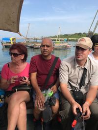 Young couple sitting on boat against sky