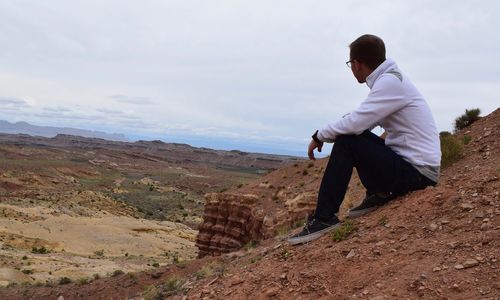 Side view of man on land against sky