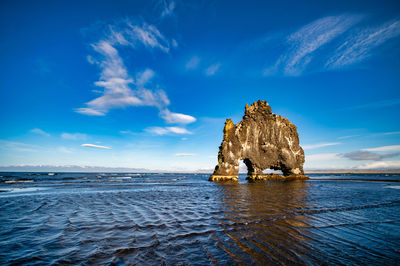 Rock formation on sea against blue sky