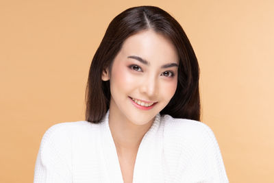 Portrait of a smiling young woman against gray background