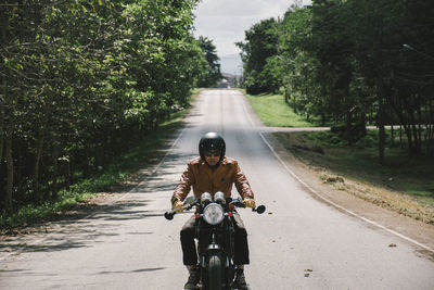 Man riding bicycle on road against trees