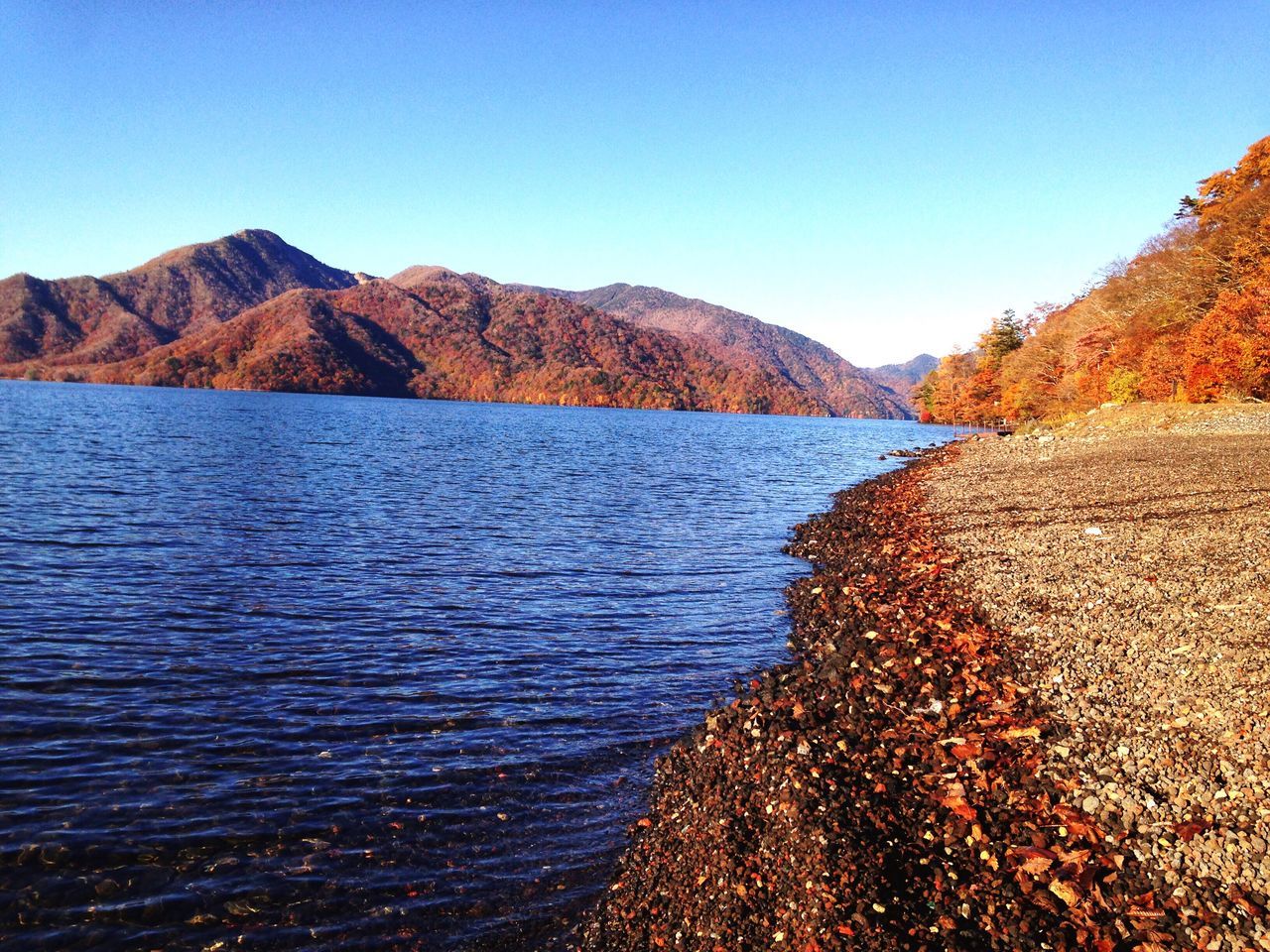 mountain, water, tranquil scene, scenics, clear sky, blue, mountain range, tranquility, beauty in nature, lake, nature, non-urban scene, remote, day, calm, outdoors, no people, tourism, physical geography, waterfront, sea, geology, majestic, vacations, seascape, rocky mountains