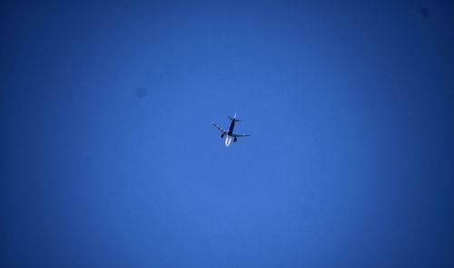 Low angle view of airplane against clear blue sky