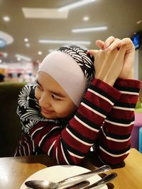 Girl looking away while sitting at table in restaurant