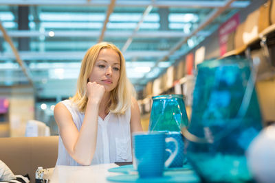 Young woman looking down while sitting on table