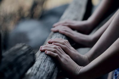Cropped image of hands touching wooden railing