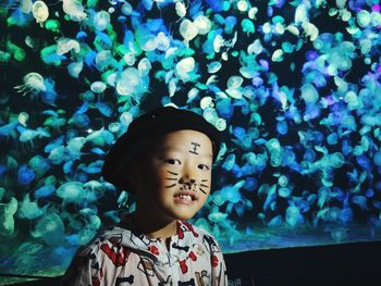 Portrait of cute boy standing against jellyfishes in aquarium