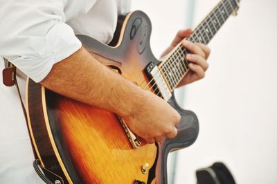 Midsection of man playing guitar