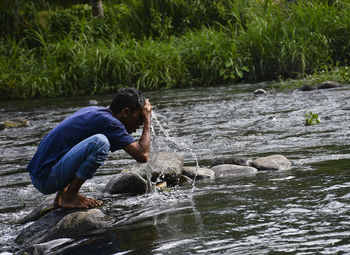 Man splashing water on rock at river