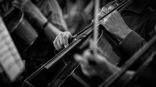 Midsection of musicians playing cellos at festival