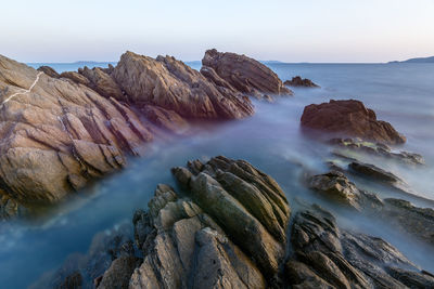 Rock formations in sea against sky