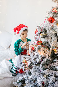 Portrait of smiling girl standing by christmas tree