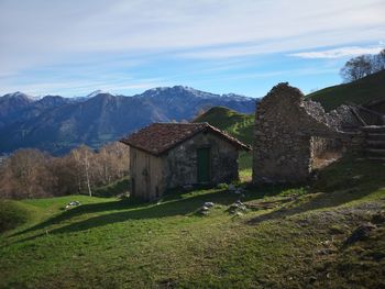 House on field by mountains against sky