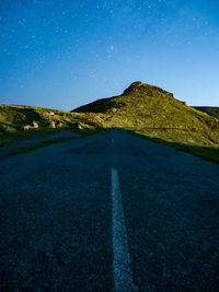 Road amidst landscape against clear blue sky at night