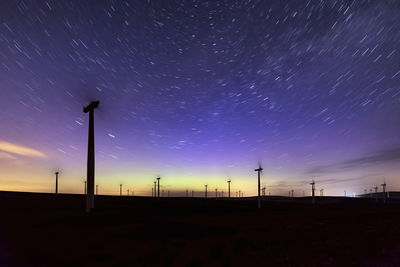 Low angle view of electricity pylon against sky during sunset