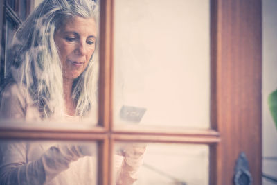 Woman holding phone by window