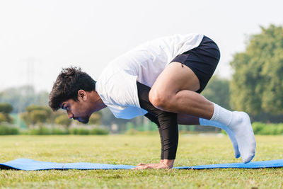 Young sportsman balancing on his hands, doing handstand in the park. young male working out .