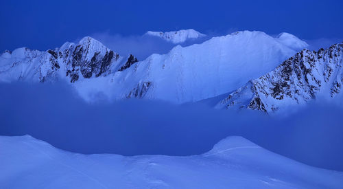 Scenic view of snowcapped mountains against blue sky