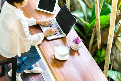 Midsection of woman holding smart phone on table