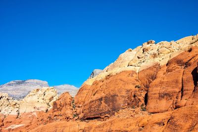 Low angle view of desert against clear blue sky