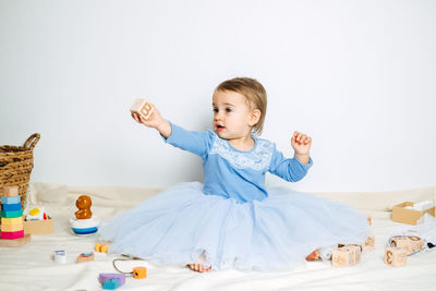 Cute baby girl in blue princess dress playing with toys at home. kids dresses for prom and birthday
