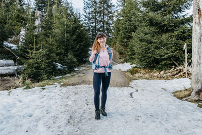 A  beautiful girl walks in the forest with a hiking backpack. happy female traveler enjoying nature