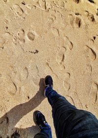 Low section of man standing on sand
