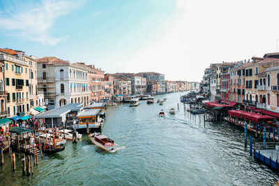 Boats in canal amidst buildings in city against sky