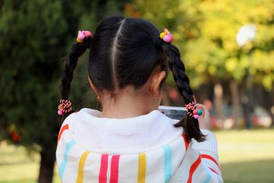 Rear view of young woman standing against trees
