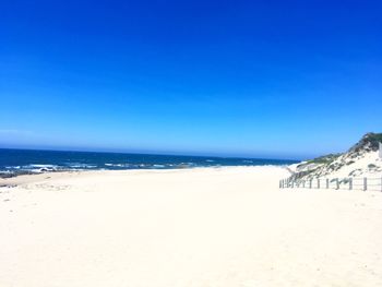 Scenic view of beach against clear blue sky