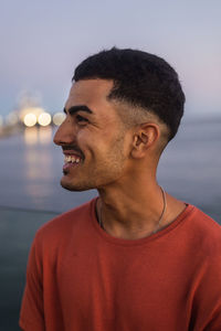 Portrait of young man looking away against sea