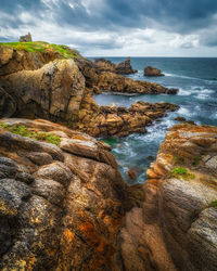 Rock formation on beach against sky