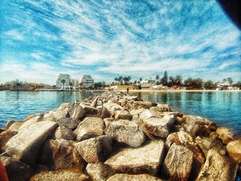 Scenic view of rocks by river against sky