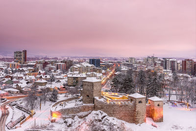 High angle view of snow covered buildings against sky during sunset