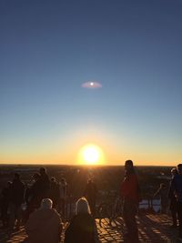 Silhouette people at beach against clear sky during sunset