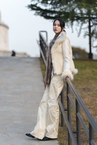 Portrait of young woman walking on footpath