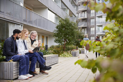 Men and woman with laptop sitting on bench in courtyard