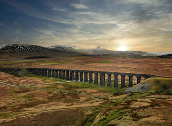 Bridge over land against sky during sunset